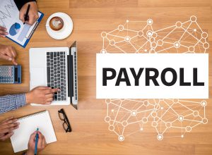 PAYROLL PAYROLL Business team hands at work with financial reports and a laptop